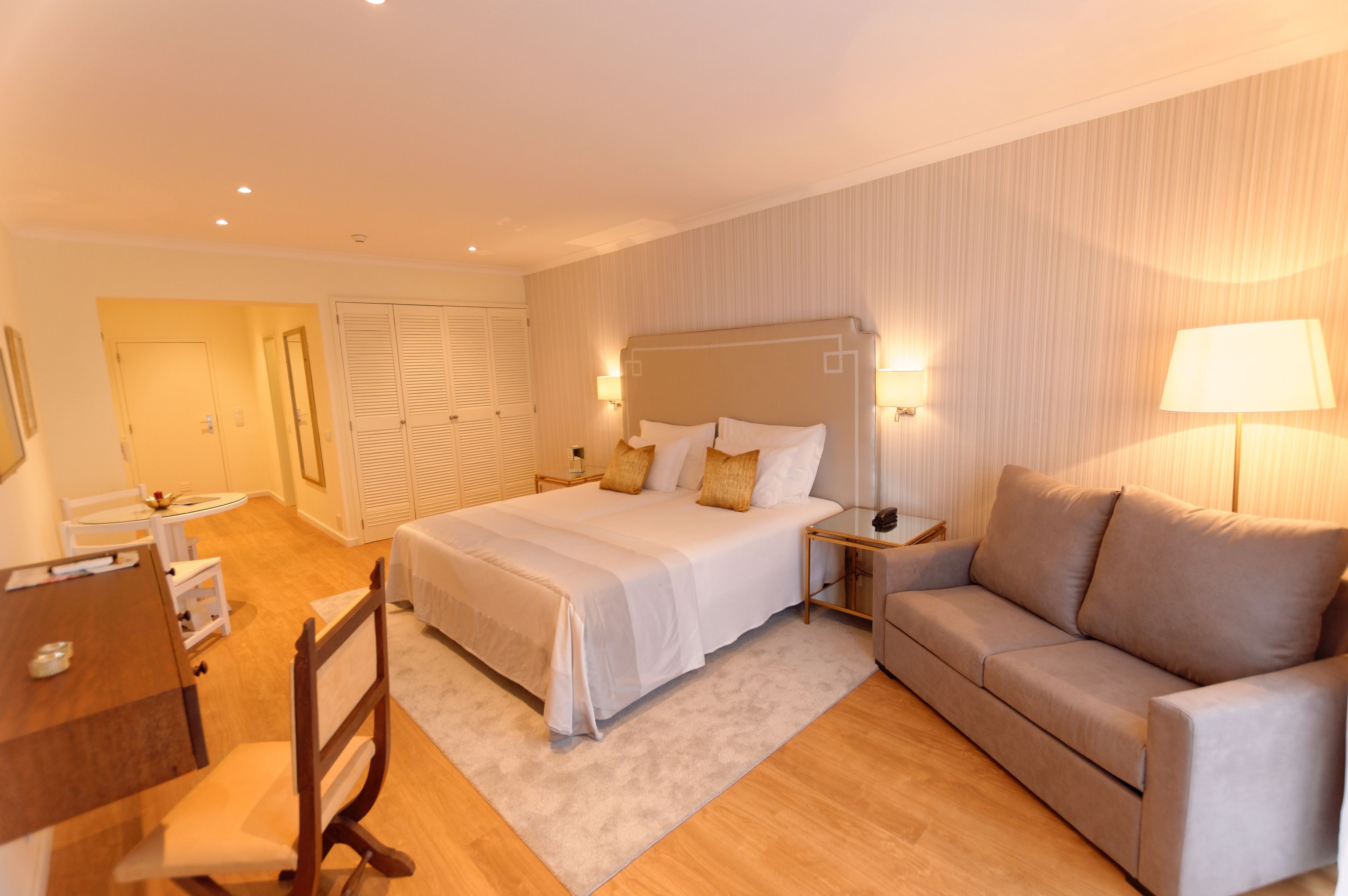 Una habitación de hotel con una cama, un sofá, un escritorio y una silla.