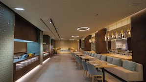 A modern restaurant with a long counter, multiple tables, and a bar area. - Vila Baleira Porto Santo (Porto Santo)