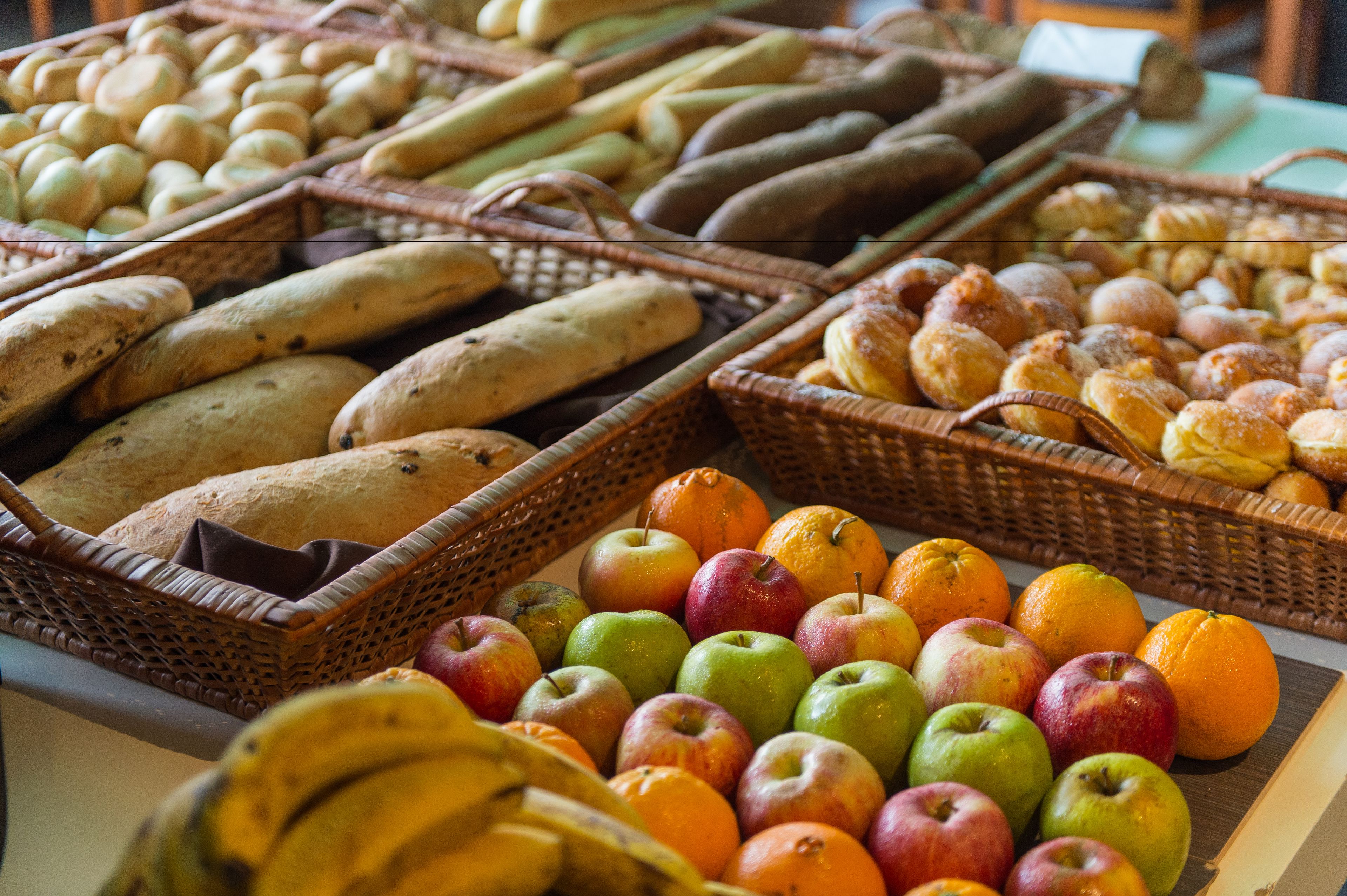 Verschiedene Brotsorten und Früchte in Körben präsentiert.