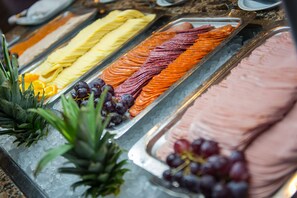 Un bufé con diversas frutas y un trozo grande de carne.