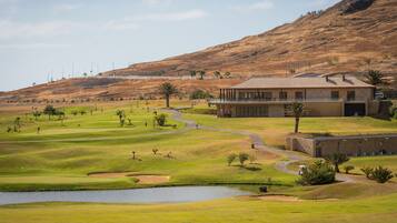 Enjoy a round of golf on our well-maintained course, featuring a clubhouse with a flat roof and scenic views.