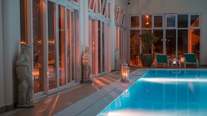 A pool area with statues, a lantern, and outdoor seating. - Vila Baleira Porto Santo (Porto Santo)