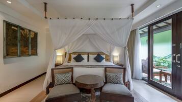 A room with a four-poster bed, a round table, two chairs, and a view through a glass door.