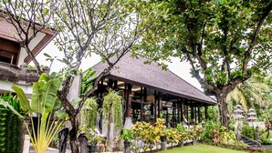 A covered outdoor area with a thatched roof, surrounded by lush greenery and potted plants. - Rama Beach Resort and Villas (Kuta)