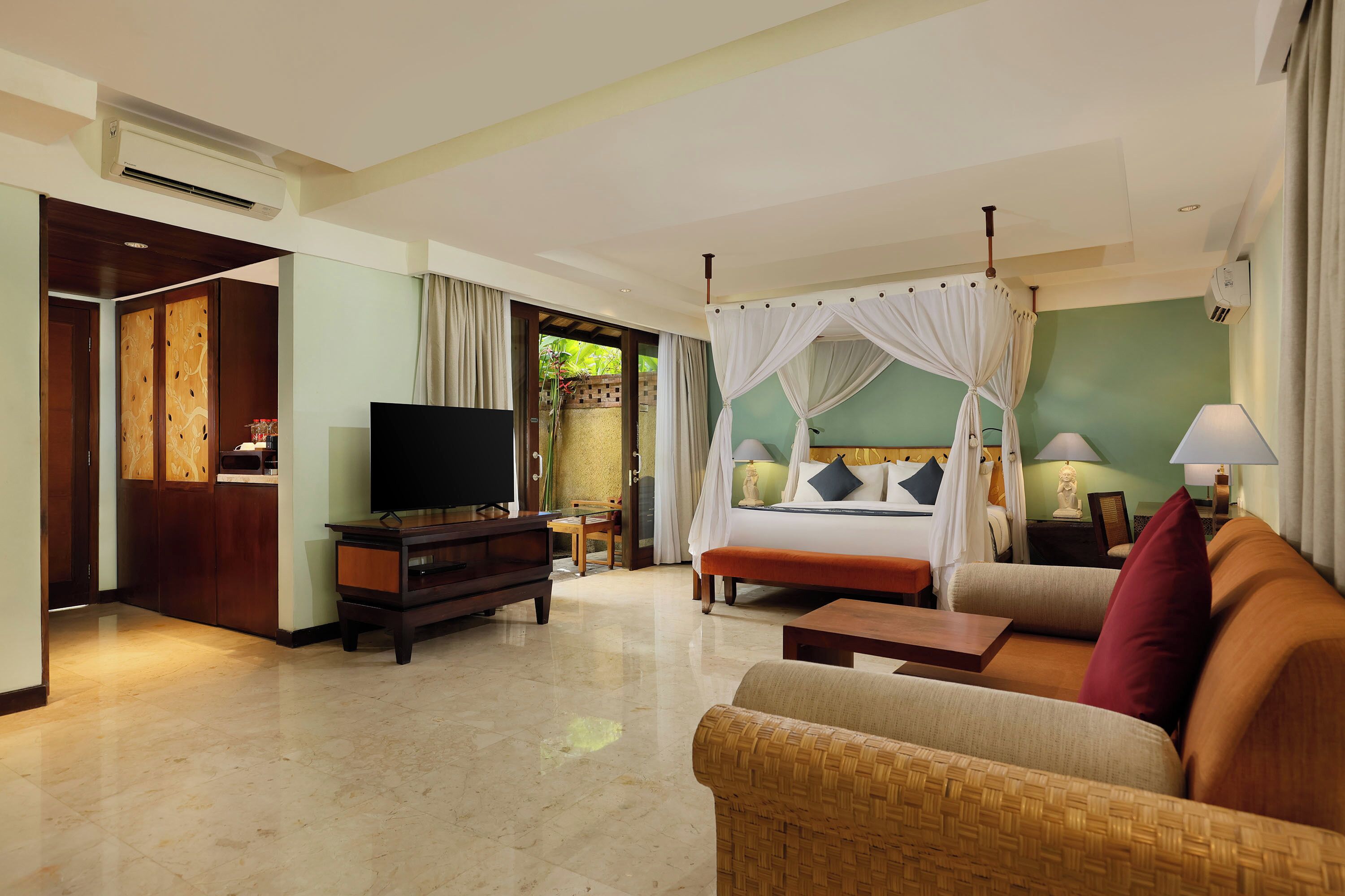 A hotel room with a bed, a TV, a sofa, a coffee table, and a TV stand.