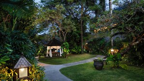 A garden pathway leading to a gazebo with a lantern, surrounded by lush greenery and a palm tree. - Rama Beach Resort and Villas (Kuta)