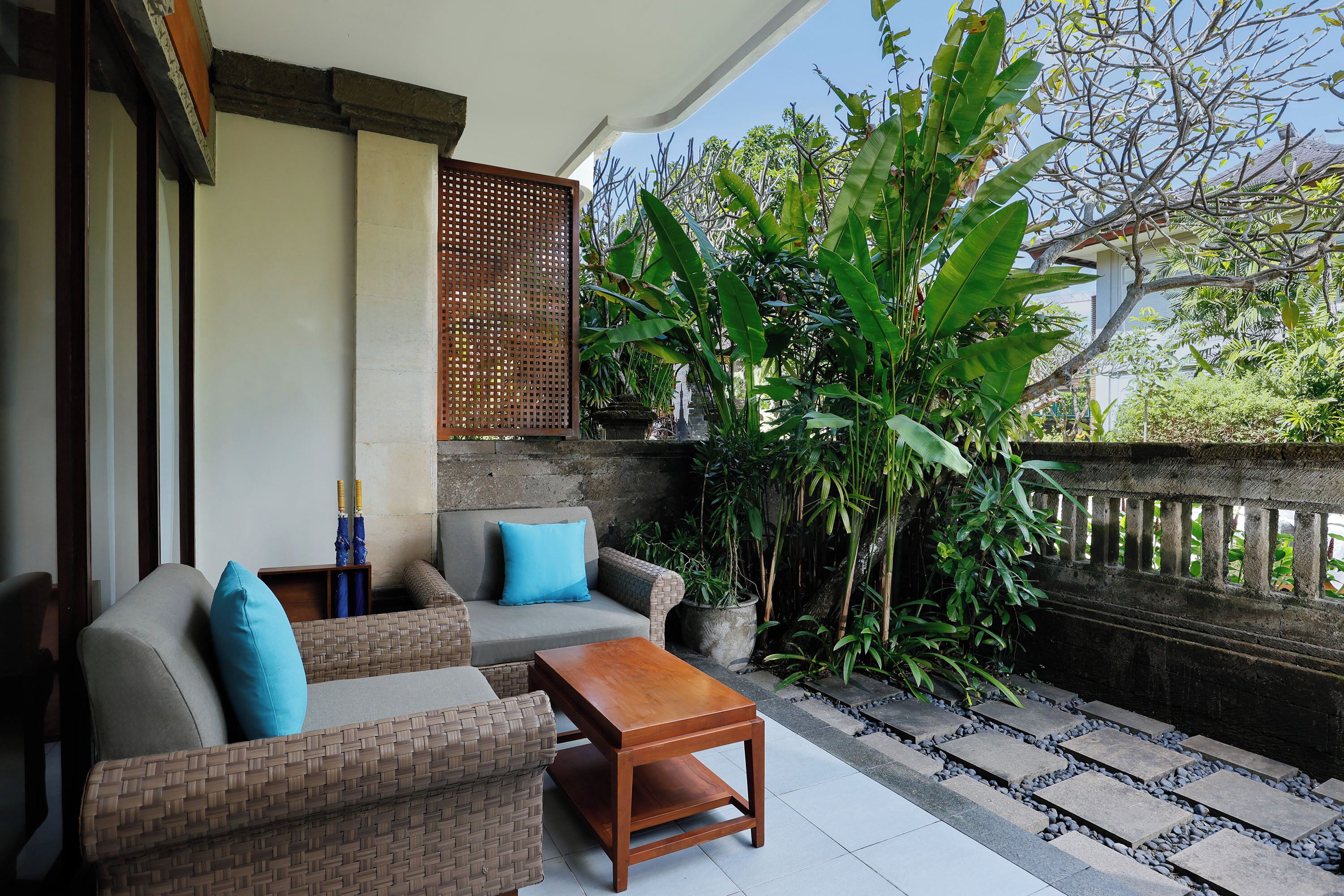 A patio with wicker furniture, a wooden table, and potted plants.