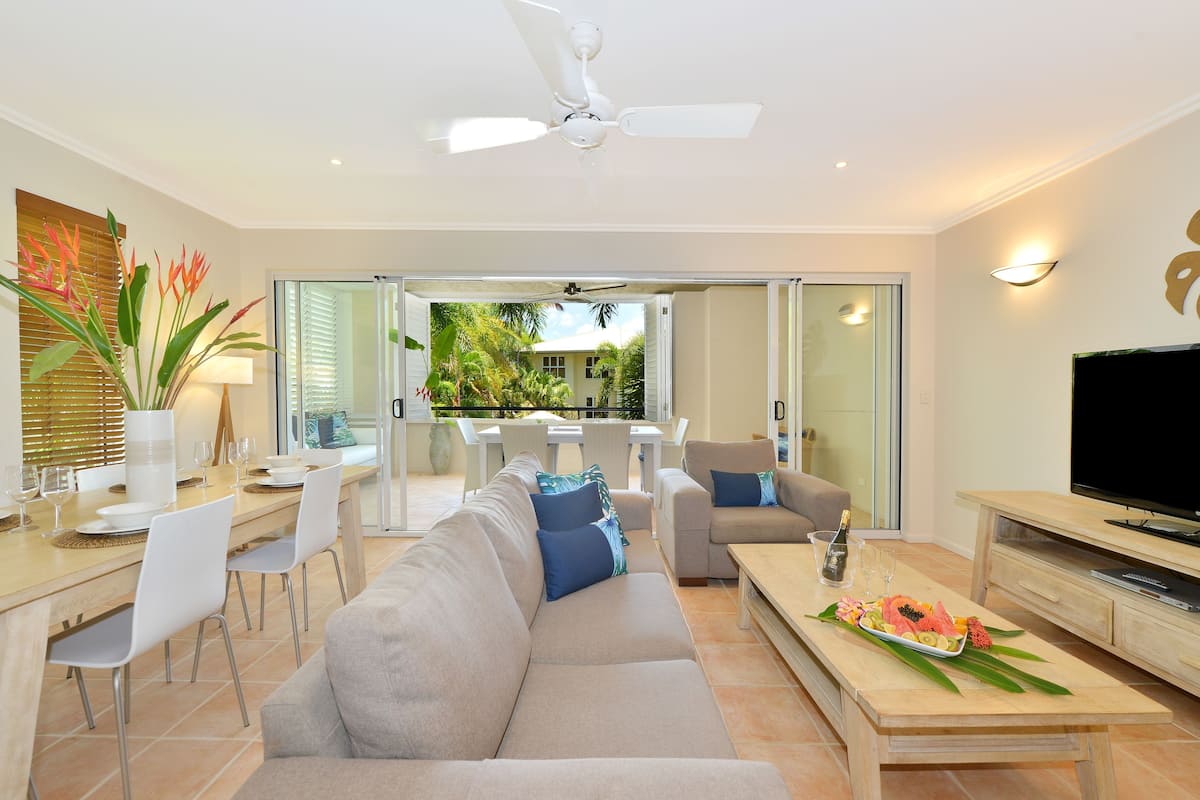 A modern living room with a sofa, dining table, and TV.