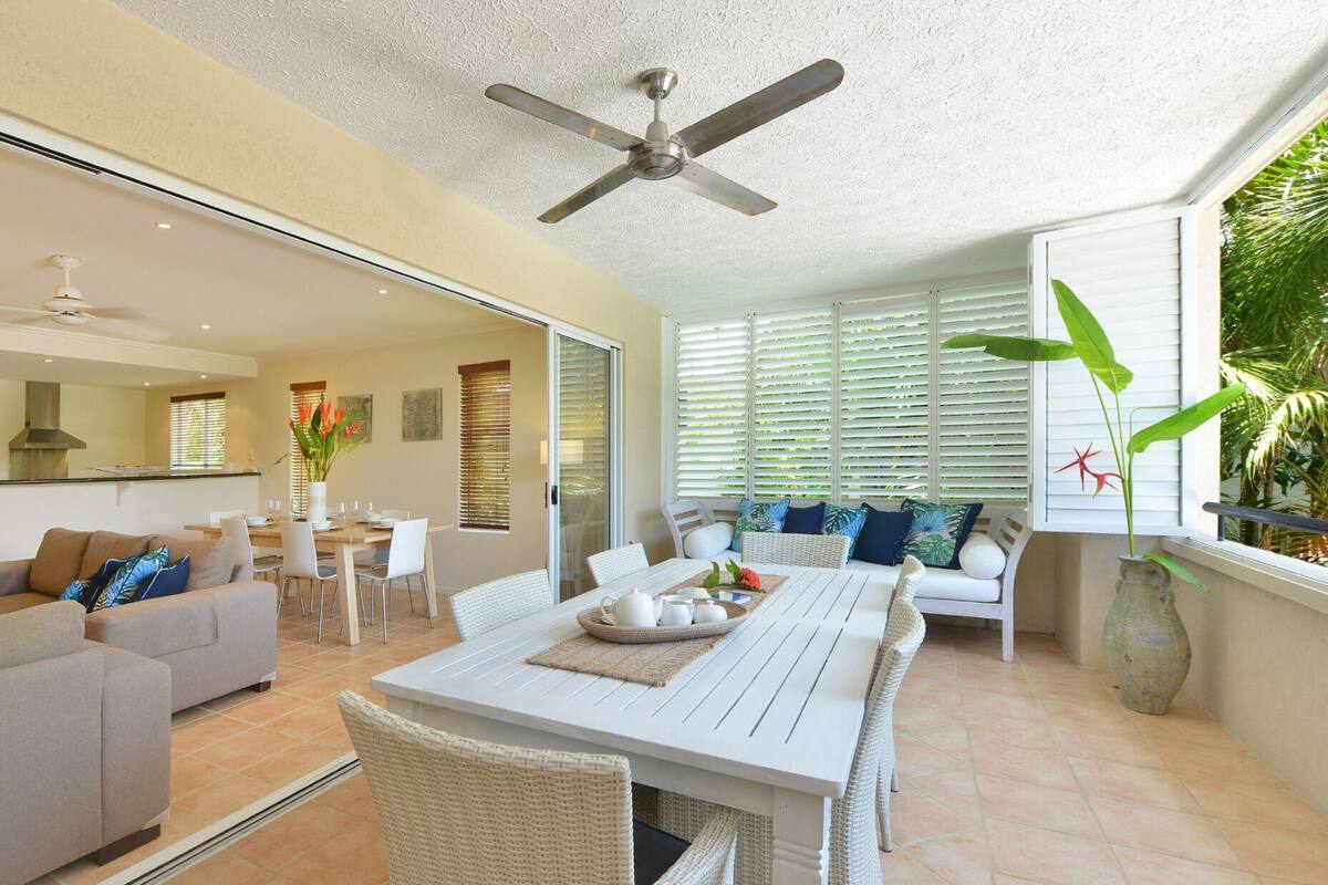 A modern living room with a dining area, a ceiling fan, and a view of the outdoors.