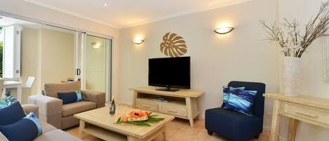 A modern living room with a flat-screen TV, comfortable seating, and a dining area.