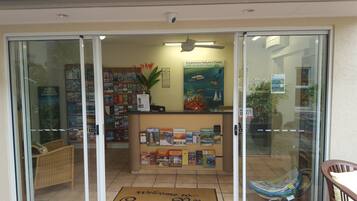 A bookstore with a glass door entrance, a welcome mat, and a variety of books on shelves.