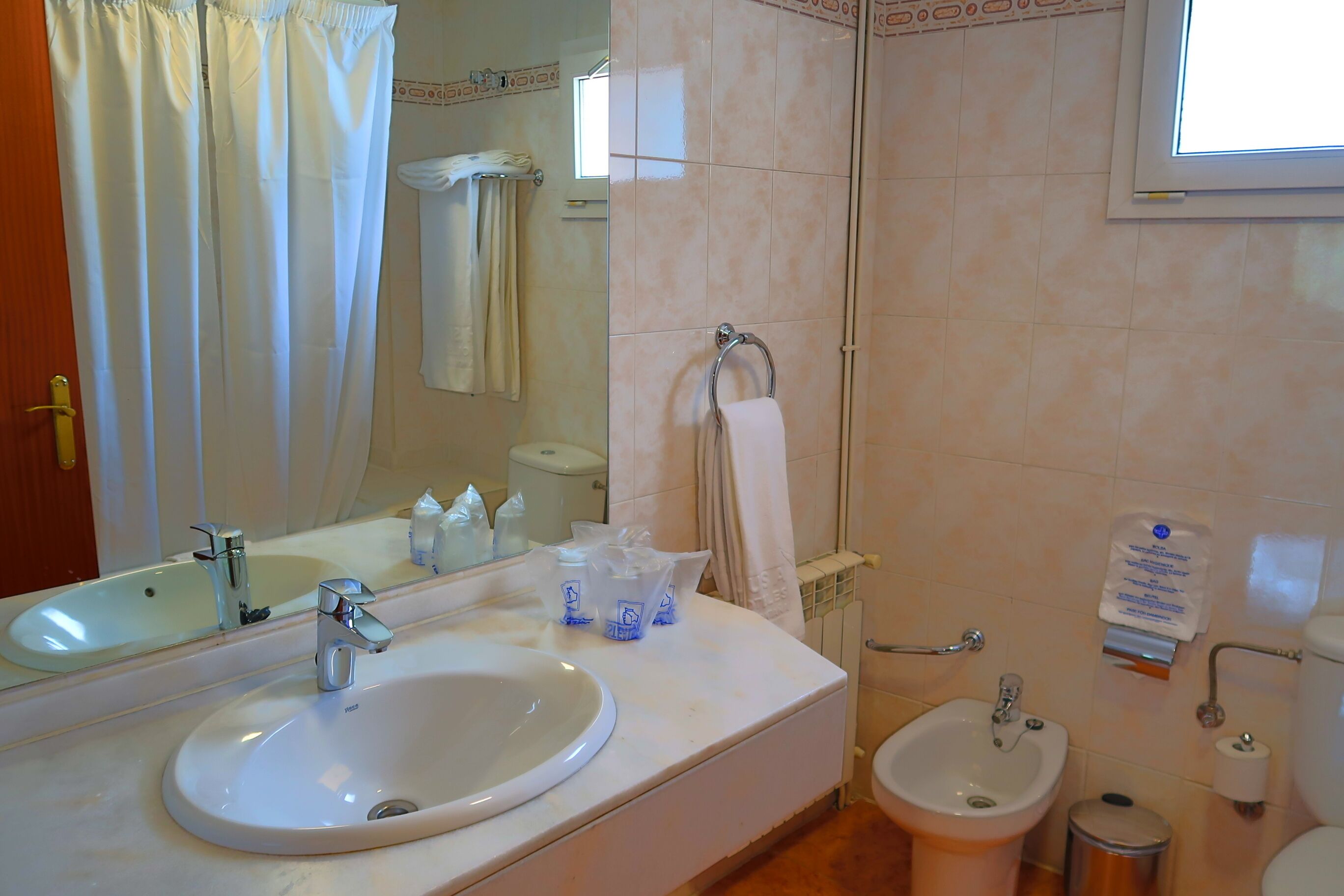 Un baño con lavamanos, bidé y espejo.
