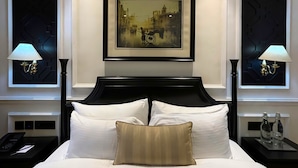 A hotel room with a large bed, two nightstands, a framed picture on the wall, and two wall-mounted lamps. - Peerless Hotel Kolkata (Kolkata)