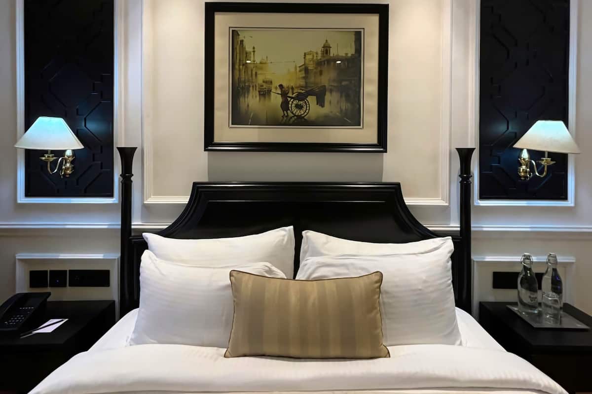 A hotel room with a large bed, two nightstands, a framed picture on the wall, and two wall-mounted lamps.