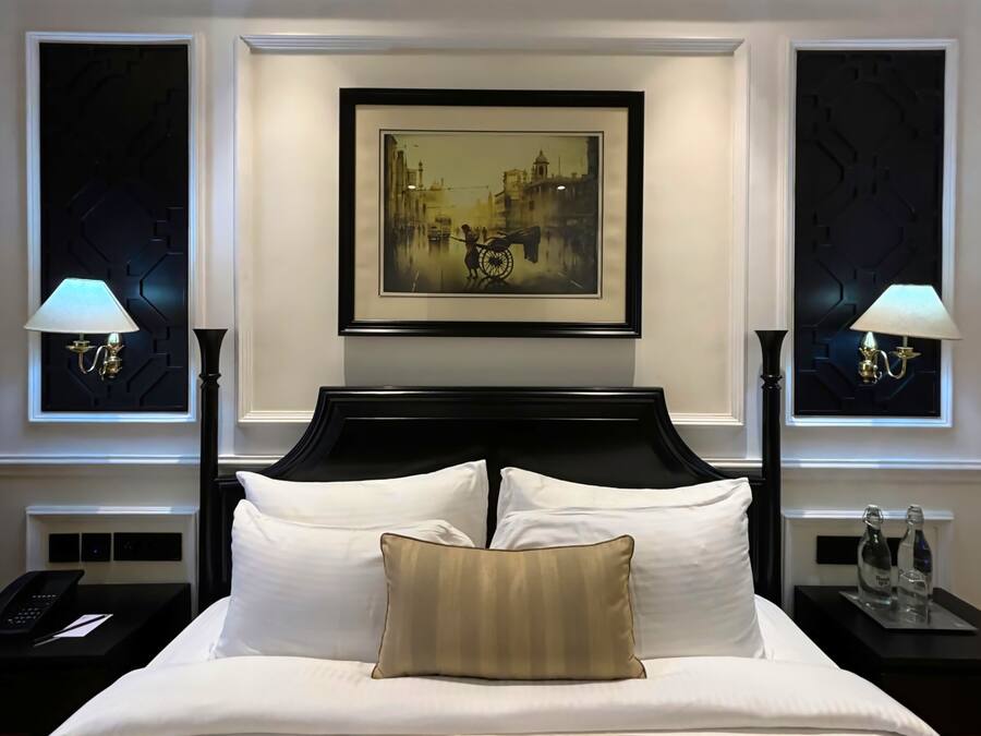 A hotel room with a large bed, two nightstands, a framed picture on the wall, and two wall-mounted lamps.