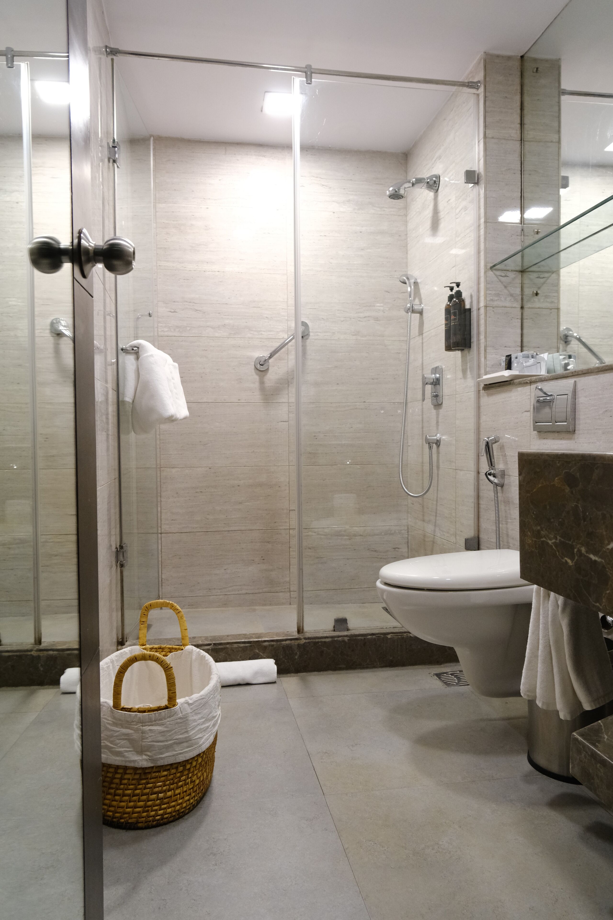 A modern bathroom with a glass-enclosed shower, a toilet, and a marble sink.