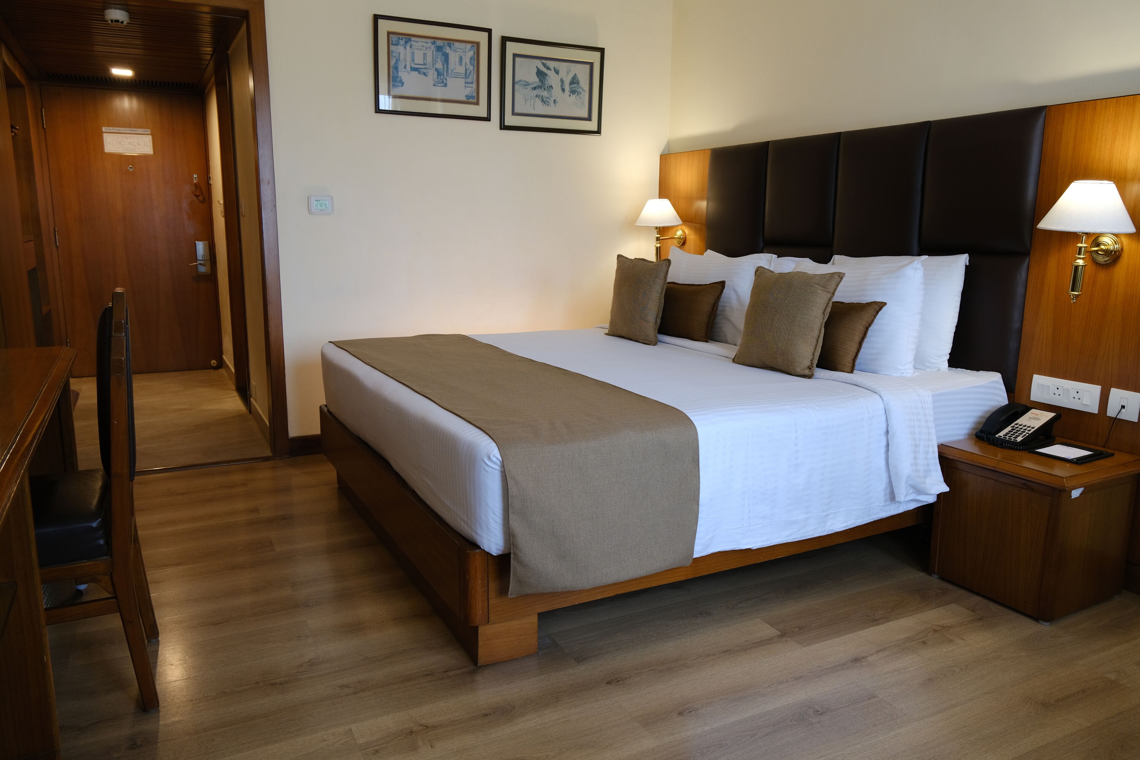Een hotelkamer met een houten bed, twee bedlampen, een telefoon en een nachtkastje van hout.