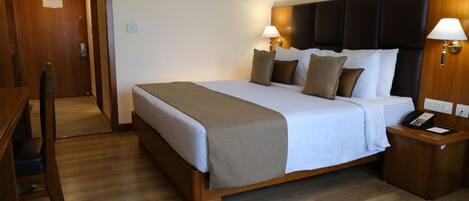 A hotel room with a wooden bed, two bedside lamps, a telephone, and a wooden nightstand.