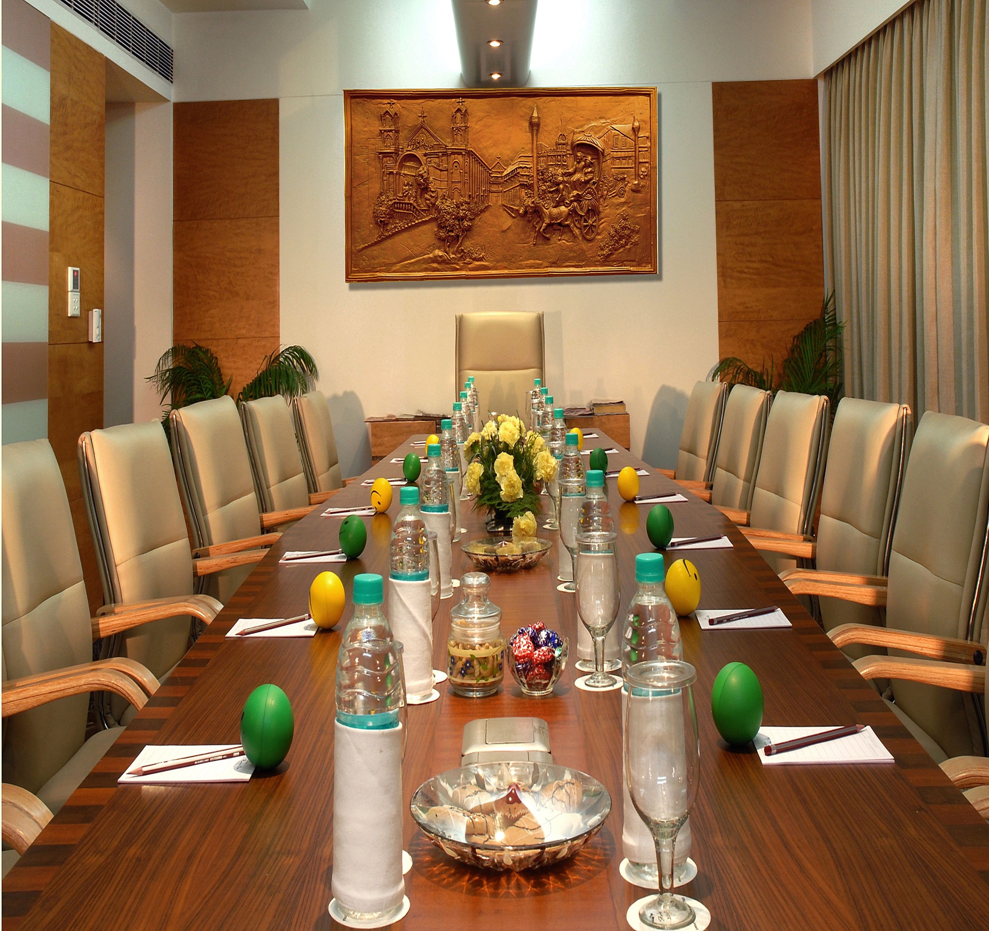 A conference room with a long table, chairs, water bottles, and a decorative centerpiece.