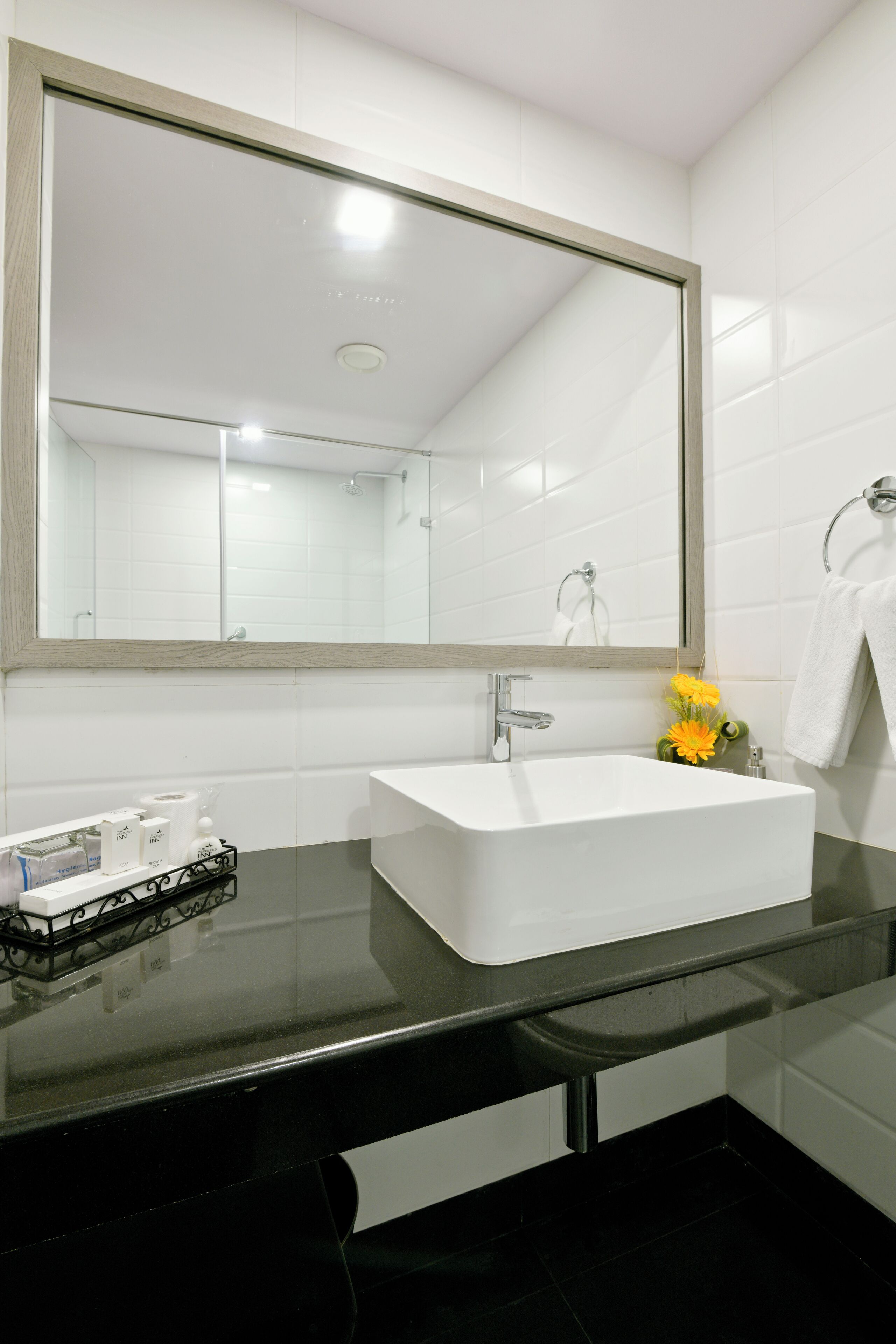 Een moderne badkamer met een witte wastafel, een grote spiegel en een zwart aanrecht.