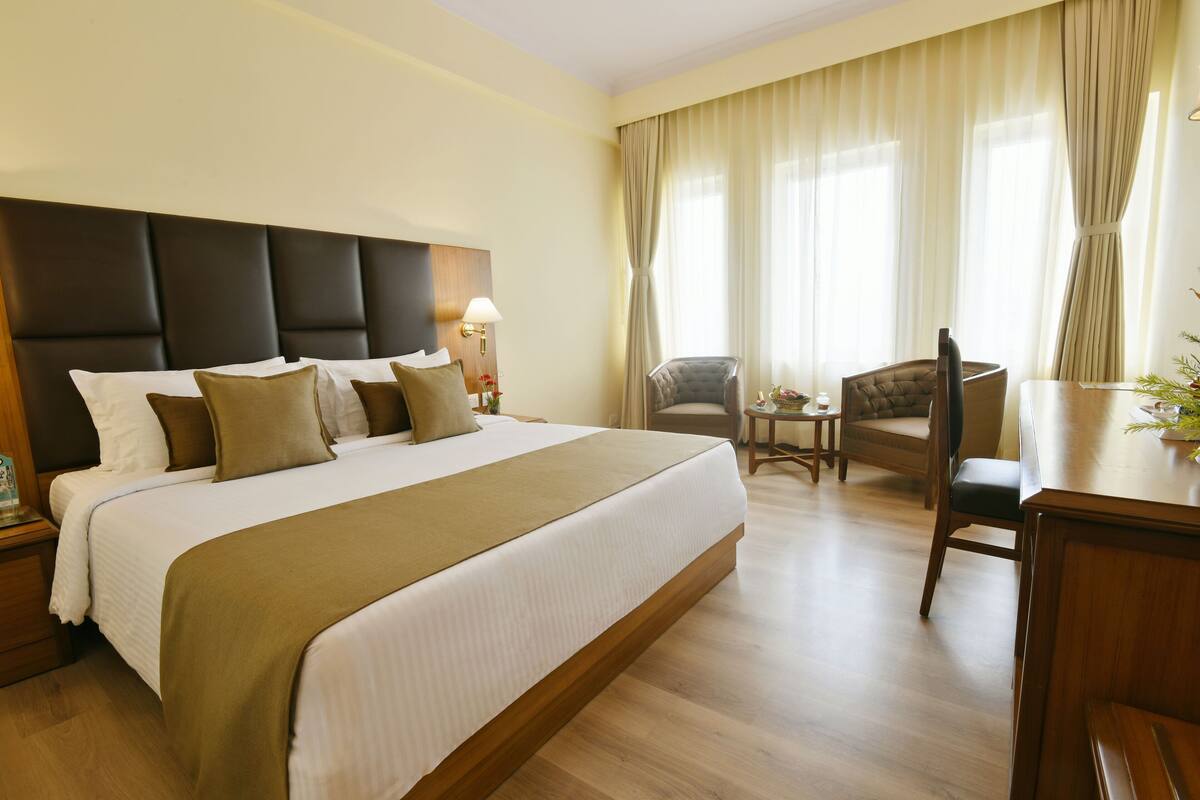A hotel room with a large bed, a desk, and a chair.