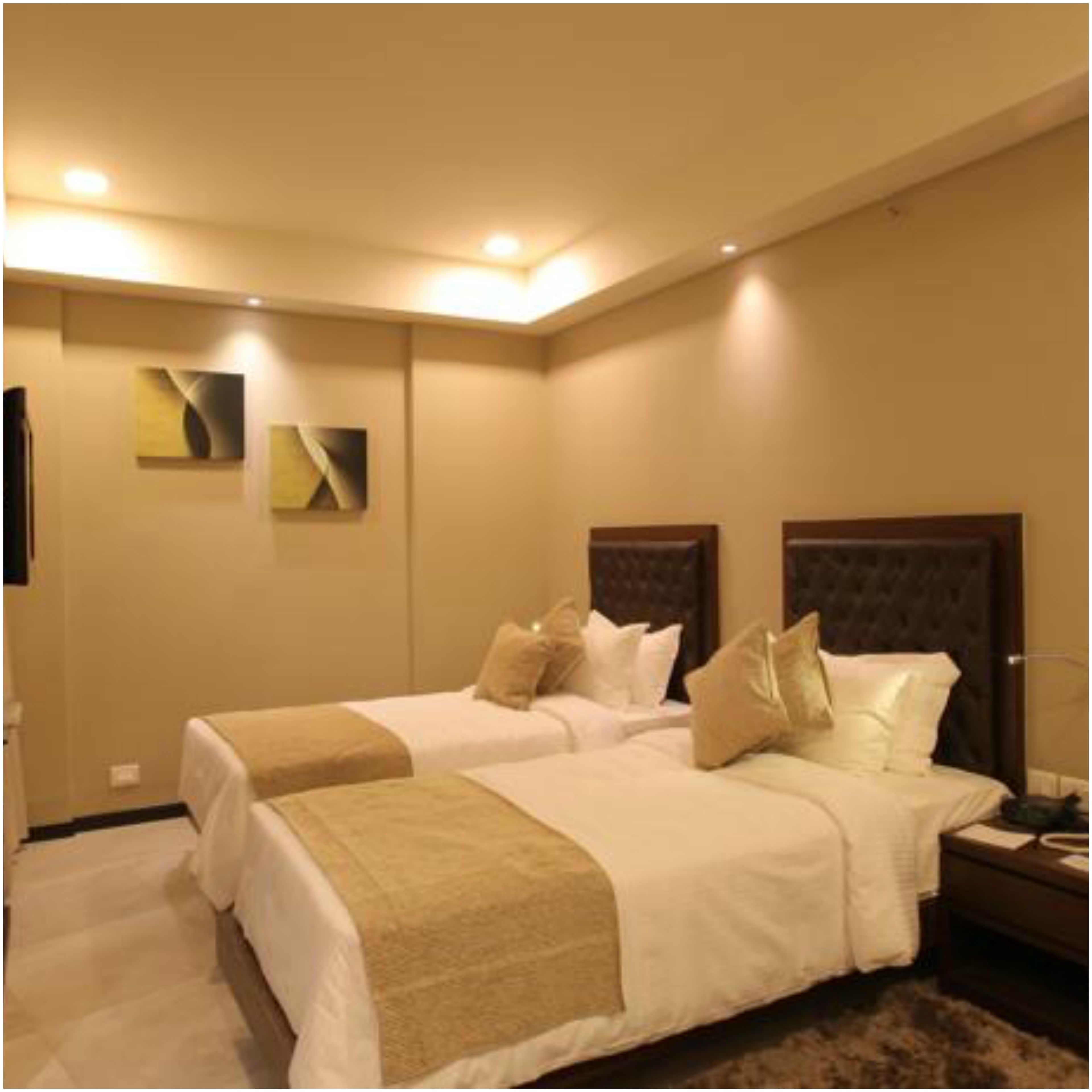 Habitación de hotel con dos camas, paredes color beige y decoración moderna.