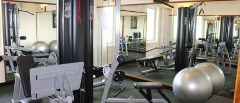Un gimnasio con equipo de ejercicio, espejos y pelotas de entrenamiento.