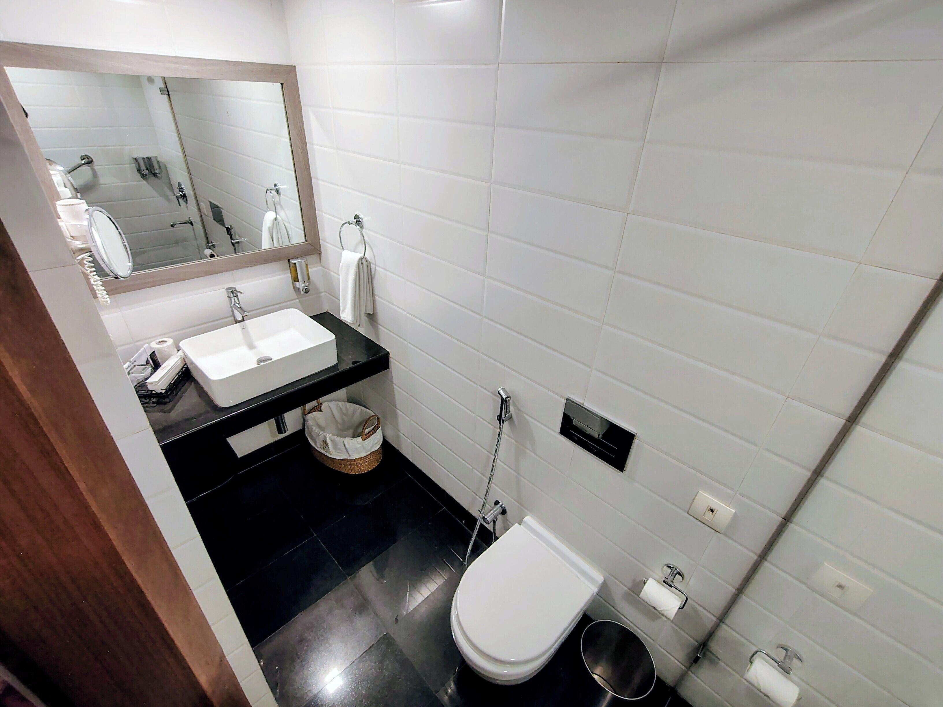 Une salle de bain avec un lavabo blanc, un miroir, des toilettes et une douche.