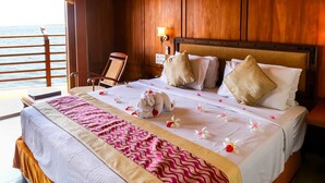 Quarto de hotel com uma cama, uma cadeira, uma mesa de cabeceira e vista para o mar.