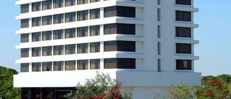 Un edificio de varios pisos con fachada plana, numerosas ventanas y exterior blanco.