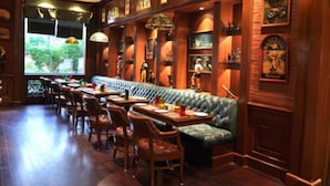 Un restaurante con paneles de madera, una barra alargada y un banco con cojín verde.