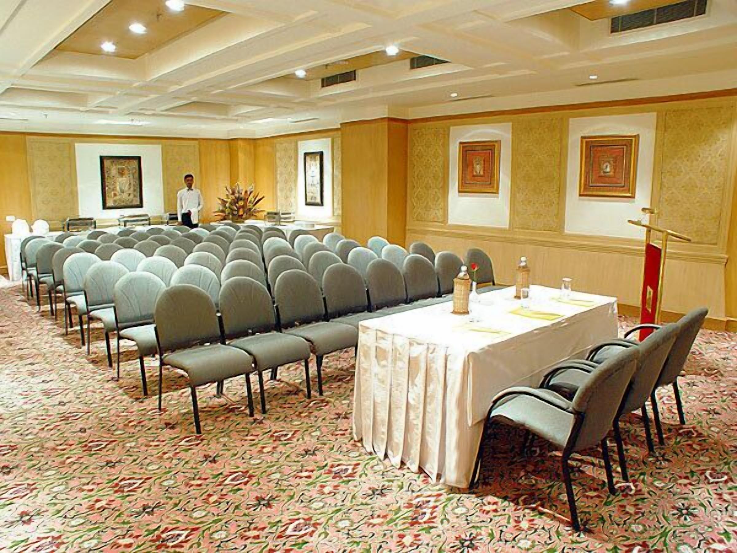 A conference room with rows of chairs, a long table, and a podium.