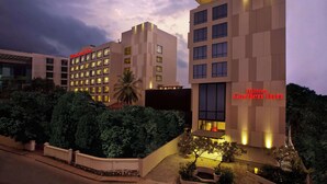Un hotel moderno con varios pisos, una entrada bien iluminada y un jardín ajardinado.