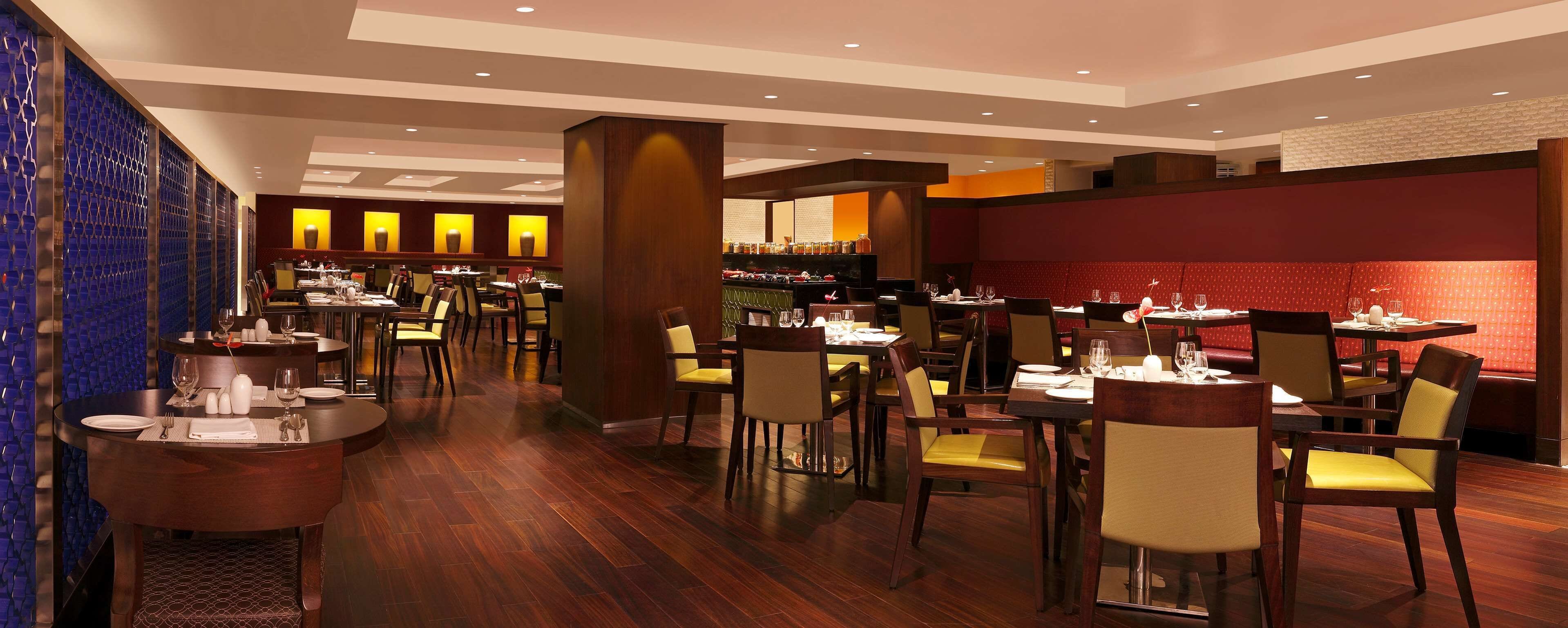 A restaurant with multiple dining areas, wooden flooring, and a bar area with shelves of bottles.