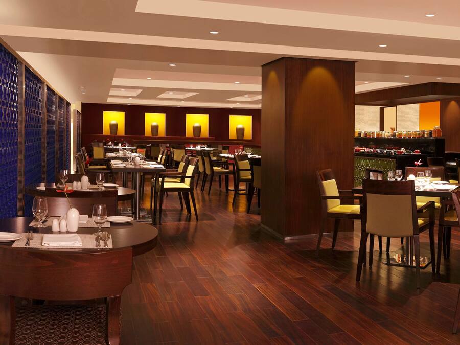A restaurant with round tables and chairs, a bar area, and a patterned wall.