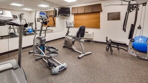 A fitness center with treadmills, elliptical machines, a stationary bike, and a blue exercise ball.