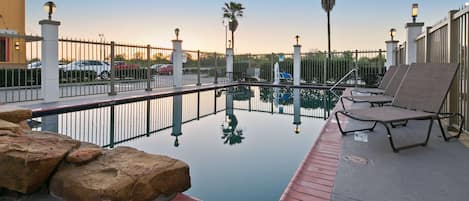 Una piscina al aire libre, sillones reclinables de piscina