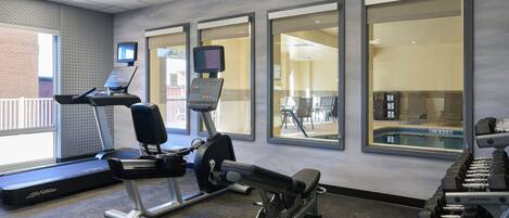 Uma academia com equipamentos de cardio, aparelhos de musculação e halteres.