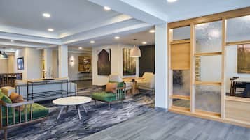 A spacious lobby with seating areas, a large window with frosted glass, and artwork on the walls.