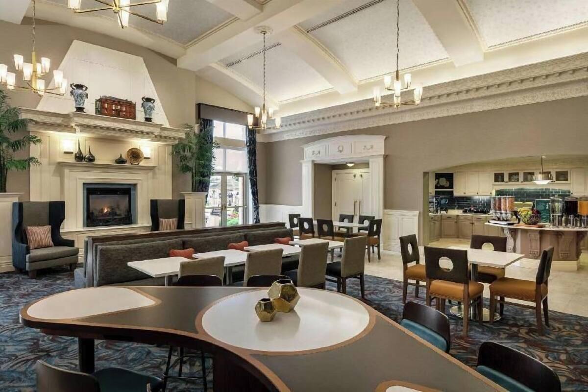 A spacious dining area with high ceilings, a fireplace, and a view of the kitchen.