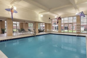 An indoor swimming pool with lounge chairs and tables, large windows, and hanging decorations. - Homewood Suites by Hilton Harrisburg East-Hershey Area (Harrisburg)