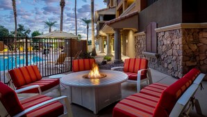 A poolside area with a fire pit, red-striped chairs, and a stone wall. - Holiday Inn Phoenix - Chandler by IHG (Chandler)