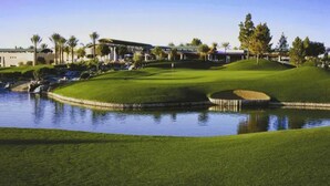 A golf course with a pond, a clubhouse, and surrounding trees. - Holiday Inn Phoenix - Chandler by IHG (Chandler)