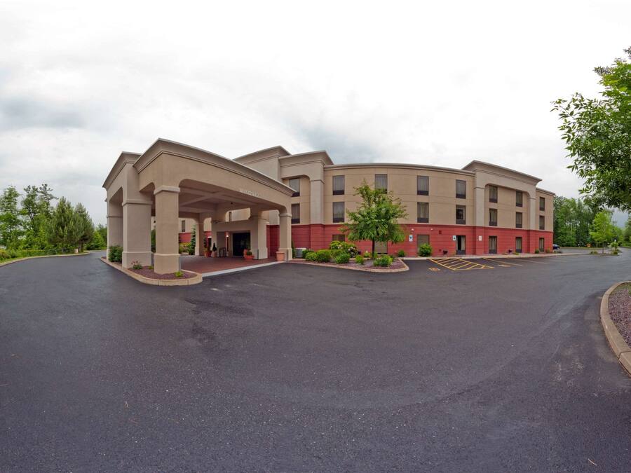 A hotel with a curved facade, a covered entrance, and a parking lot.