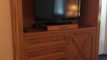 Un mueble de madera con centro de entretenimiento, televisor de pantalla plana, cajones y un cubo de basura.