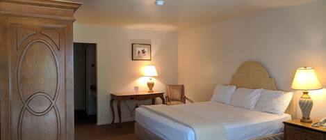 A hotel room with a bed, bedside tables, a desk, and a wardrobe.