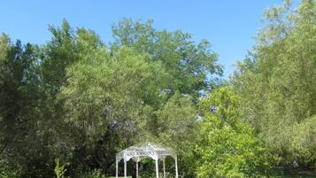 Un jardín cuidado con un pabellón y cielo despejado.