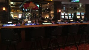 A bar area with a neon sign reading "Tack House Bar," multiple slot machines, and a menu board displaying "Vienna Beef."