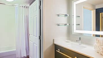 A bathroom with a white sink, a mirror, and a towel on the counter.