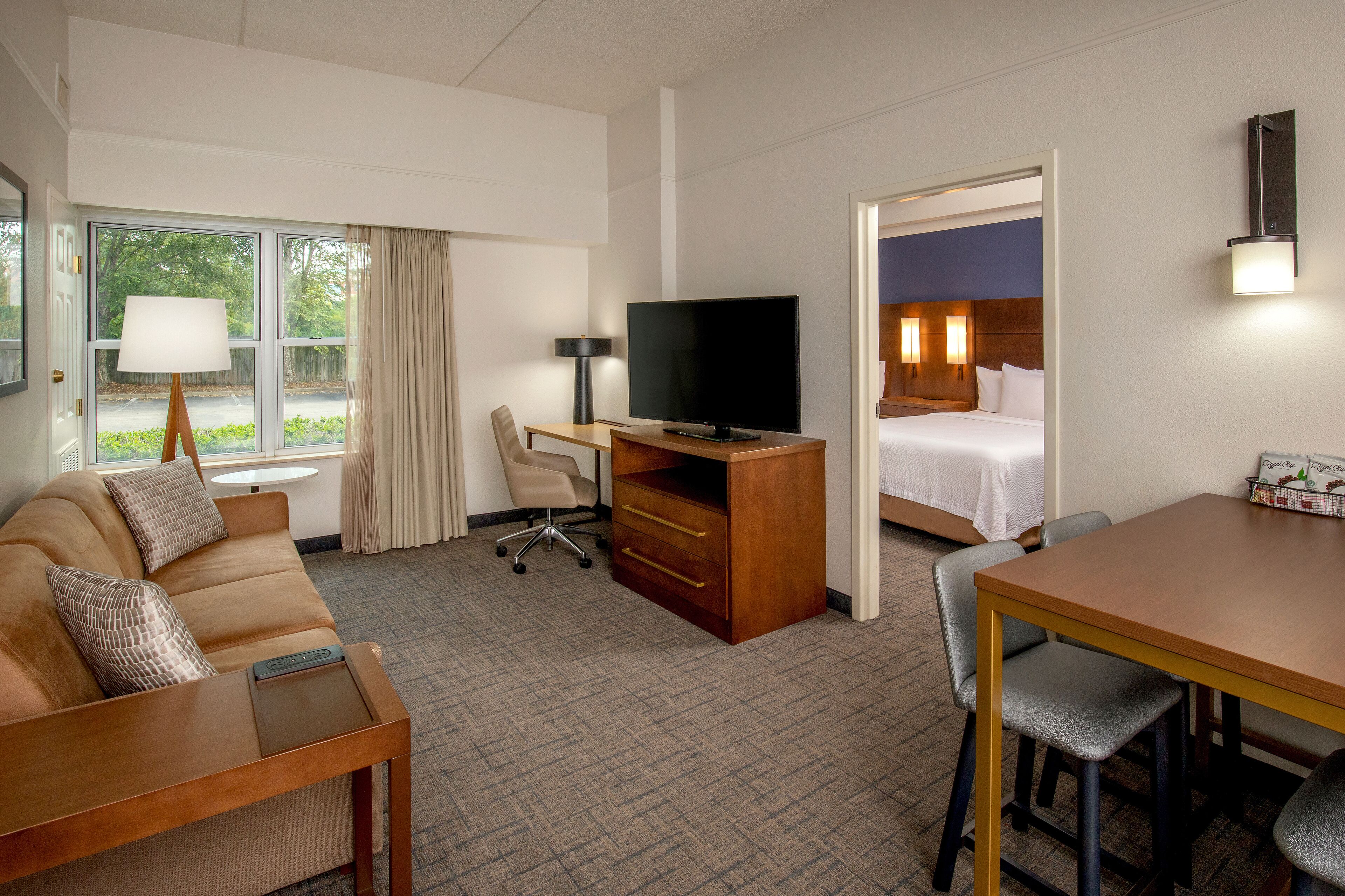 A hotel room with a sofa, desk, TV, and a bed.